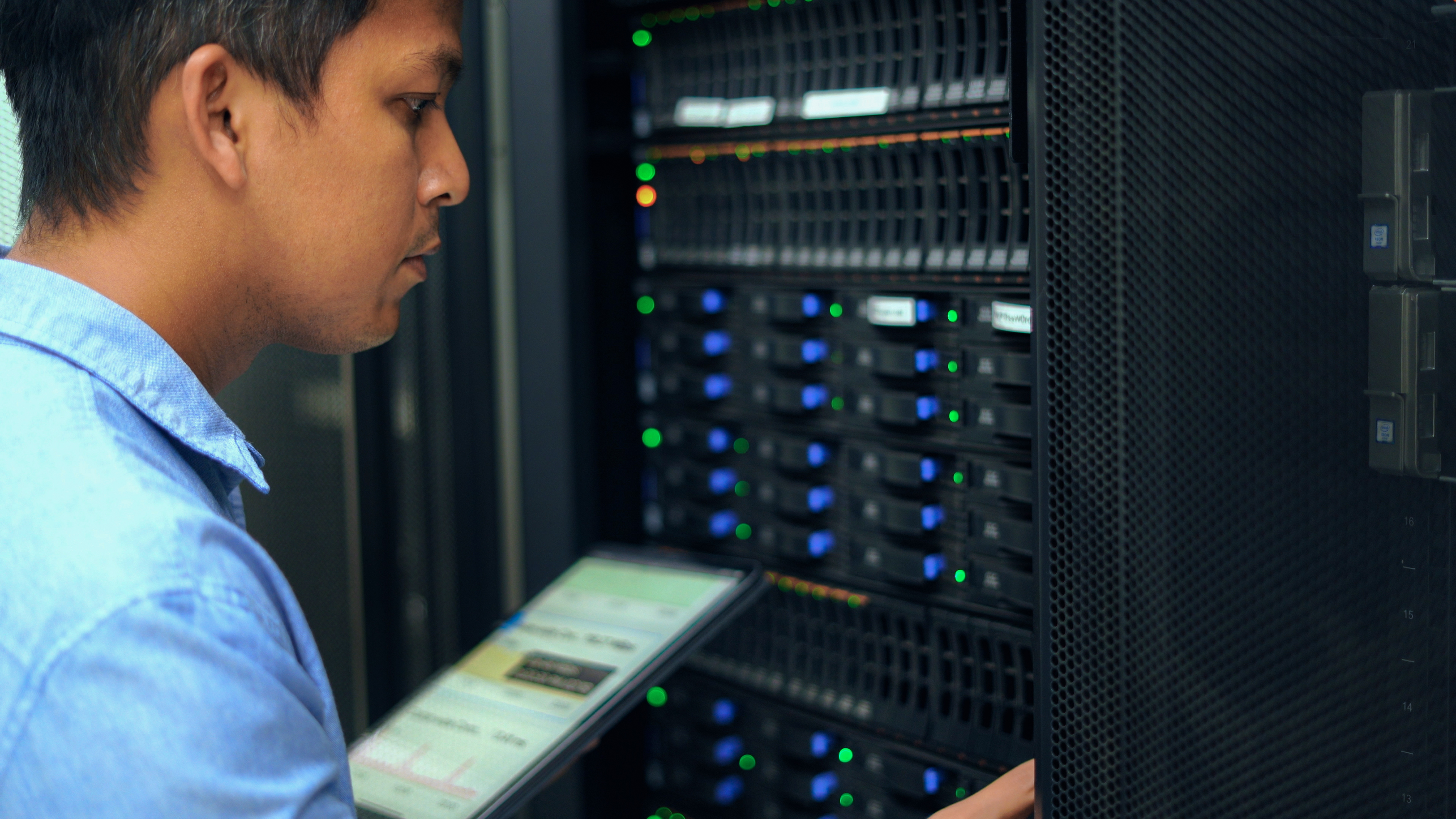 System administrator working with tablet in data center.